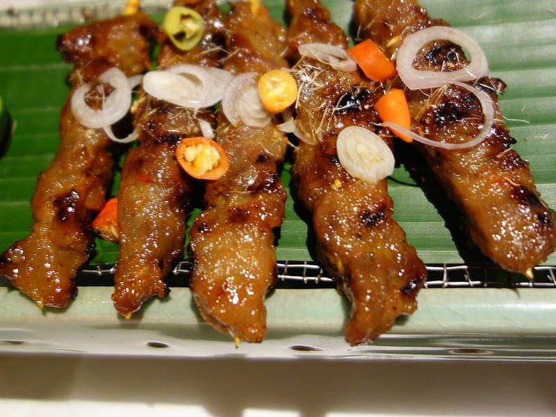 Sate ayam bakar dengan irisan bawang merah dan cabai di atas daun pisang